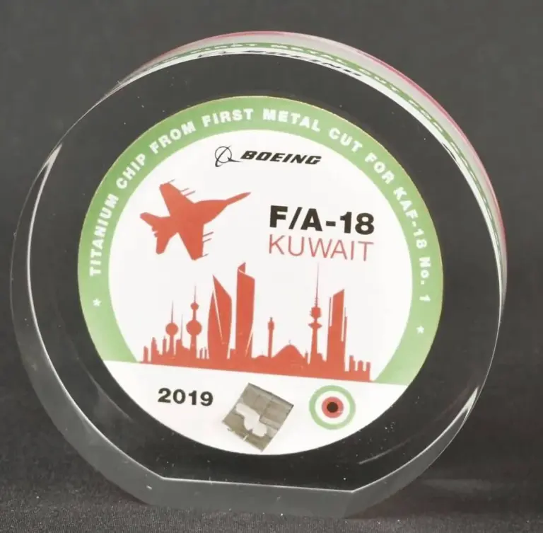 Round aerospace recognition award commemorating a titanium chip from the first metal cut for an F/A-18 Kuwait project